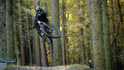 En cyklist med fuldhjelm hopper op på en Cube Stereo ONE77 Fully-mountainbike.