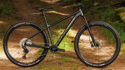 Her ses en sort Cube-mountainbike, der står på en skovvej.