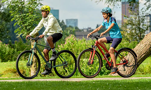 En mandlig og en kvindelig cyklist kører på crosscykler langs en park.