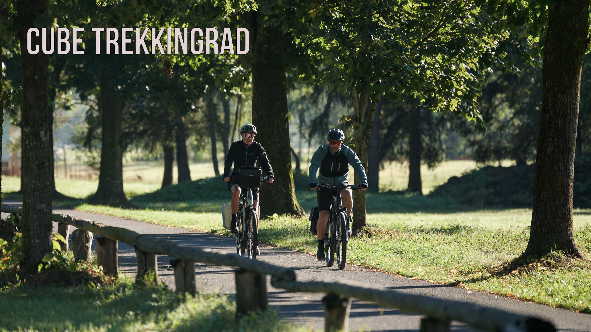 Der ses et billede med teksten »Cube Trekkingcykel«, hvor et par cykler på en cykelsti gennem en park.