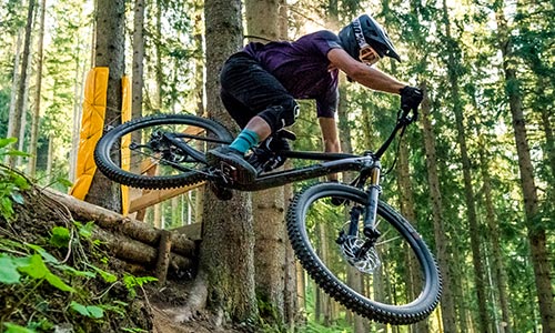 Cyklist hopper i skoven på en fuldt affjedret mountainbike