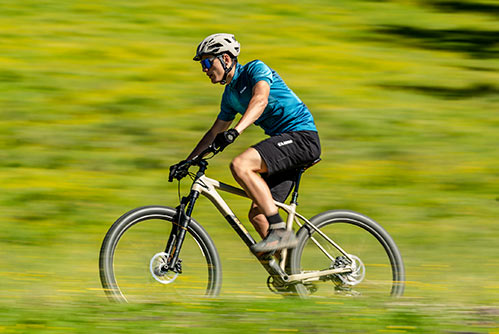 Cyklist i blå T-shirt og hjelm på en Cube Reaction mountainbike-hardtail.