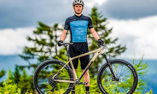 En mand i cykeltøj står bag en hardtail-mountainbike.