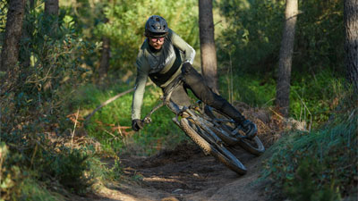 En cyklist kører på skrå gennem skoven på en Cube Stereo Fully-mountainbike.