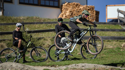 Et barn hopper på en Cube Stereo Fully-mountainbike, mens to cyklister ser på.